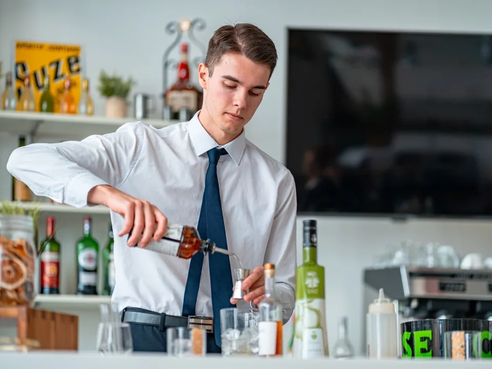 Apprenti barman versant un cocktail au bar d’application