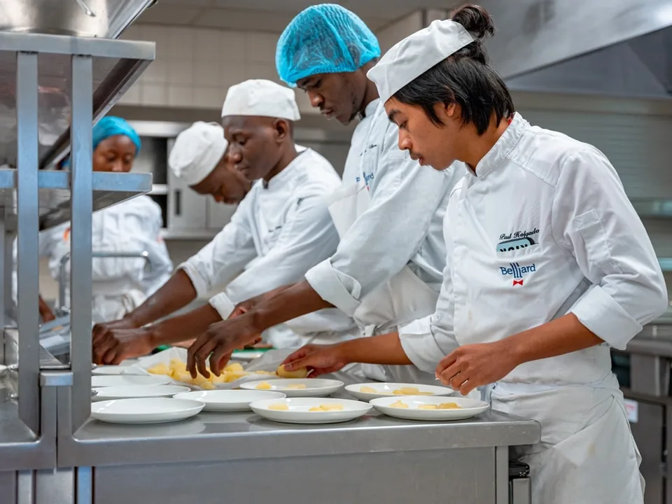 Brigade d’apprentis dressant des assiettes en cuisine