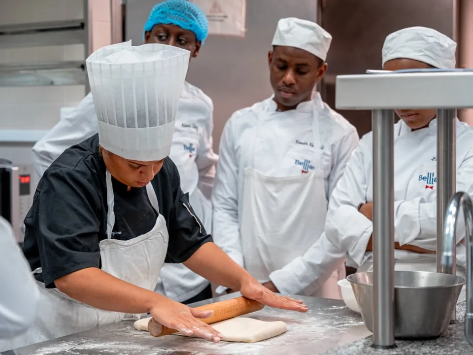 Apprentie pâtissière étalant une pâte au rouleau avec sa classe