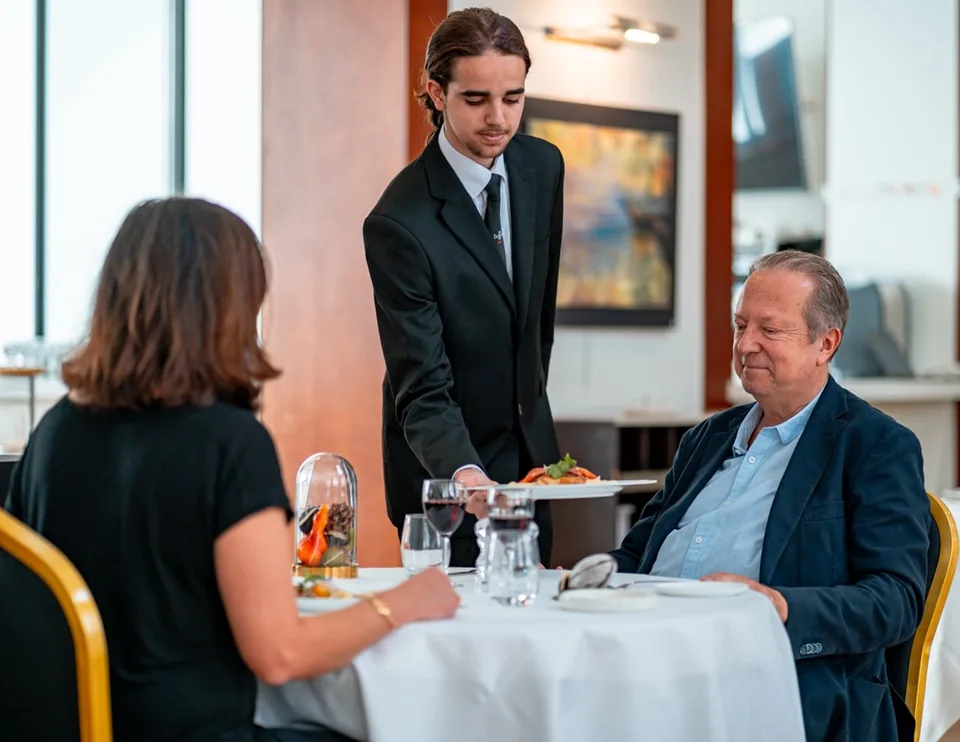Apprenti en salle servant une table au restaurant d’application